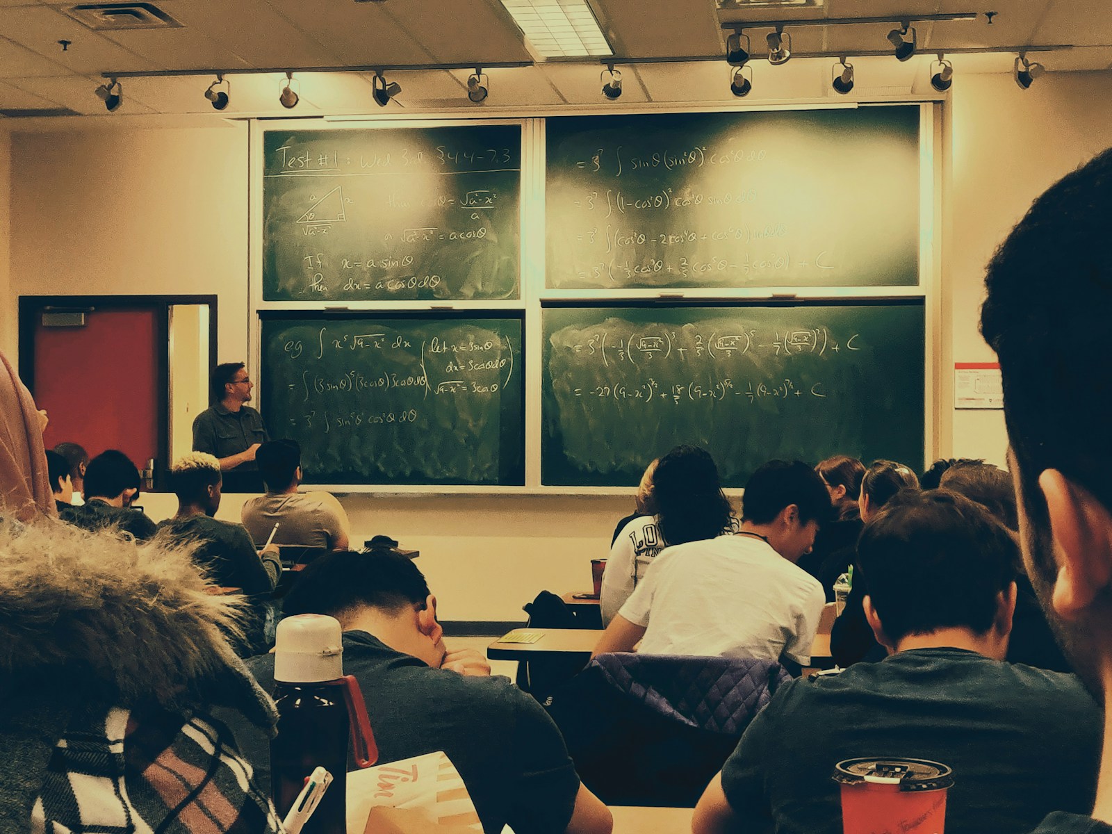 A student sitting on chairs in front of a chalkboard in an empty classroom