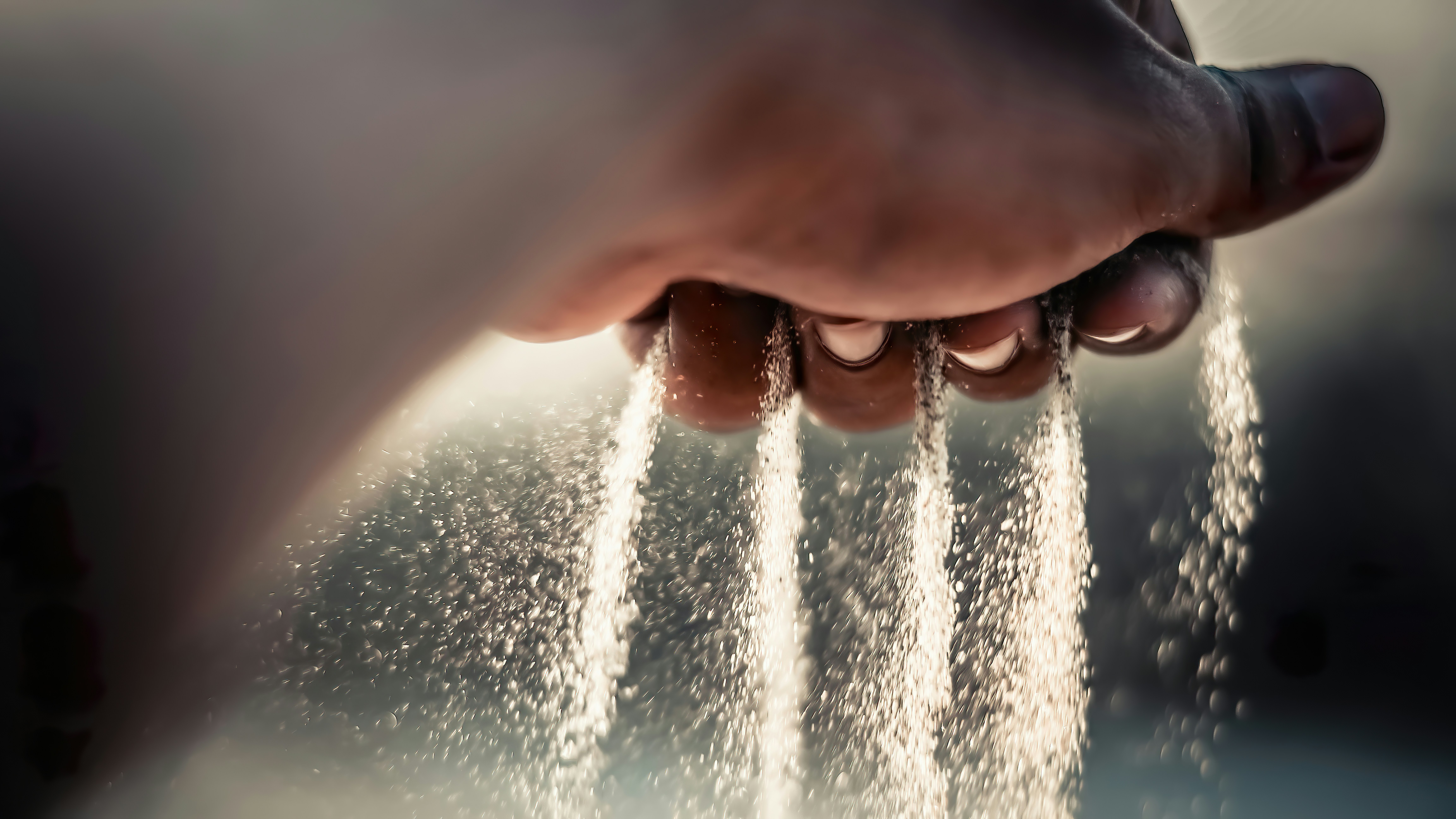 A backlit hand with water slipping through the fingers, evoking memory running out